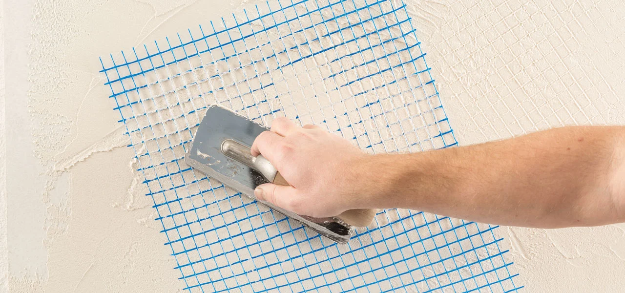Der Kalkputz wird ein zweites mal aufgetragen. Hierbei wird ein Gitternetz um eine Struktur auf der Oberfläche zu erzeugen.