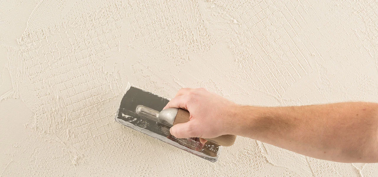 Mit einer Glättkelle wird die Kalkputz-Oberfläche geglättet.
