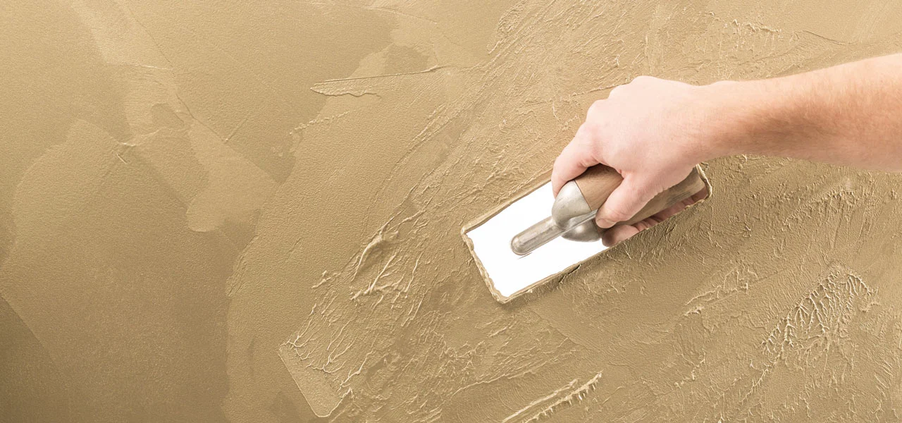 Glättspachtelmasse in gold wird mit Traufel strukturiert