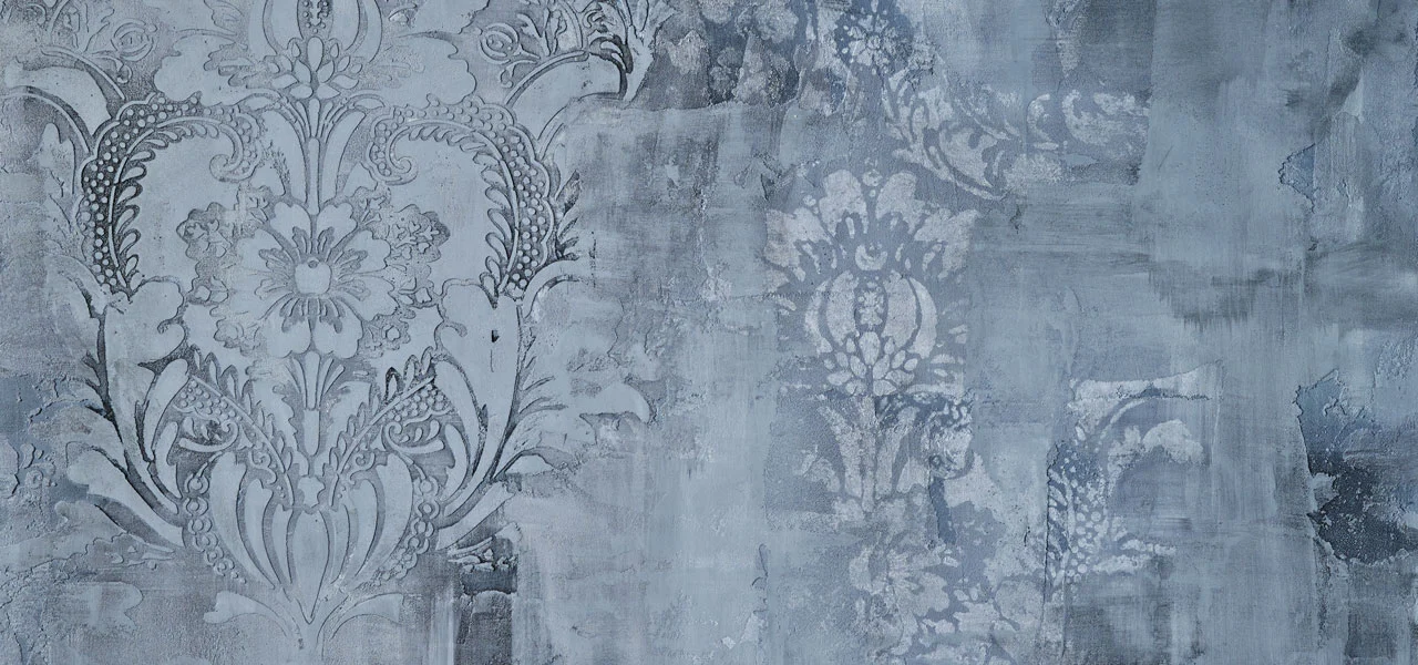 Eine graue, mit dem Kalkputz Calce Argilla verputzte Wand mit Blumenornamenten