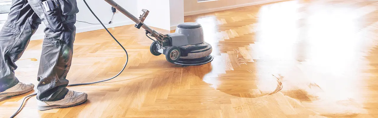 Person schleift Parkettboden mit einer Schleifmaschine
