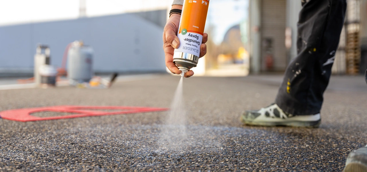 Grundierspray wird auf Asphalt aufgetragen